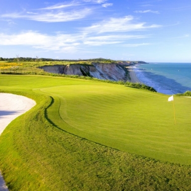 Image of golf course green between sand trap and beach