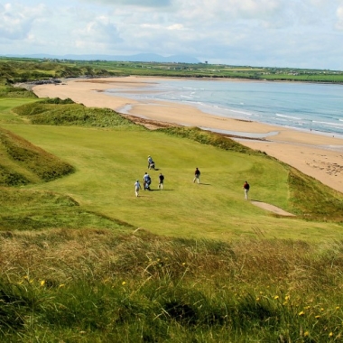 Golfers playing on a hole next to sandy beach and ocean