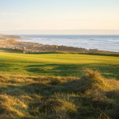 Image of golf green with rocky beach and ocean view