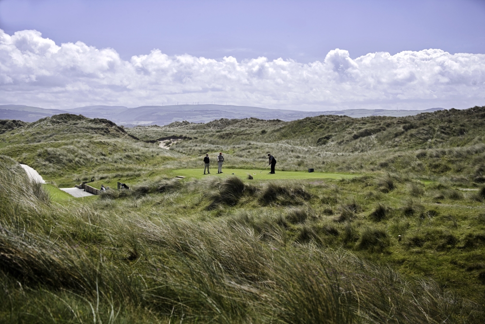 Golfers on a tee surrounded by dunes at Aberdovey