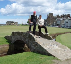 Image of two golfers standing on the iconic bridge at the St Andrews Old Course in sunshine